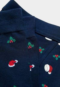 Marineblaue, festlich gestaltete Pyjamas mit weicher Textur, versehen mit roten Weihnachtsmannmützen und grünen Stechpalmenmustern, die über den Stoff verteilt sind.