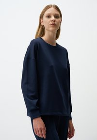 Felpa blu navy con scollo a girocollo, maniche lunghe e vestibilità rilassata. Realizzata in tessuto morbido con una texture liscia. Design semplice, senza motivi.