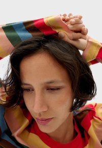 Multicolored gestreepte lange mouwen shirt met roze, blauwe, gele en bruine strepen, met een rode ronde halslijn. Katoenmix textuur.