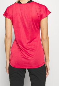 Camiseta atlética de manga corta en tejido rosa brillante, con un corte holgado y dobladillo redondeado. Cuenta con una textura suave y ligera.
