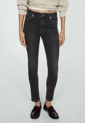 Slim-fit black denim jeans with a mid-rise waist, five pockets, and subtle fading details. Paired with dark loafers for contrast.