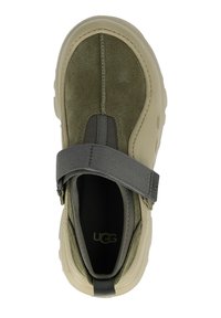 Scarpa slip-on in pelle scamosciata verde e gomma beige con cucitura verticale, cinturino elastico e soletta testurizzata. Presenta il logo UGG sul cinturino.