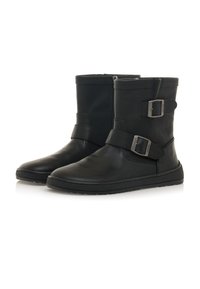 Botas de tobillo de cuero negro con dos correas ajustables y hebillas rectangulares, puntera redondeada y suela plana de goma.