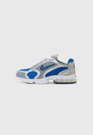 Silberner und blauer Mesh-Nike-Sneaker mit weißer Sohle, sichtbarem Luftpolster in der Ferse und blauem Swoosh-Logo mit schwarzer Umrandung an der Seite, rechte Seitenansicht.