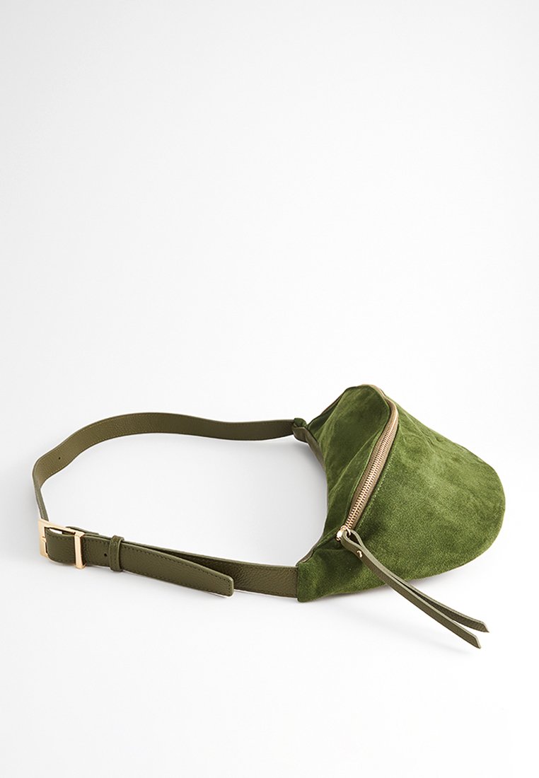 Olivgrüne Wildleder-Taillentasche mit goldenem Reißverschluss und verstellbarem Ledertrageriemen, vor einem weißen Hintergrund.