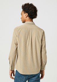 Braun-weiße karierte Langarmbluse mit einem Button-Down-Kragen, taillierter Passform und geknöpften Manschetten. Die Struktur des Baumwollstoffes ist sichtbar.