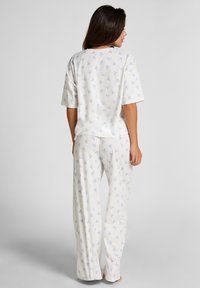 Witte pyjama set met een blauw patroon, bestaande uit een ruime korte mouwen top en brede pijpen. Gemaakt van zacht materiaal met een gladde textuur.