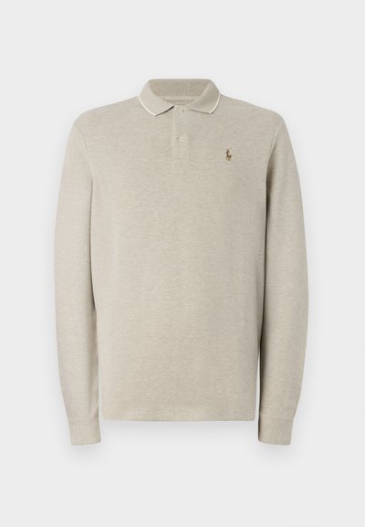 Polo de manga longa bege feito de algodão suave, com um logo bordado no peito e detalhes de contraste na gola e nos punhos.
