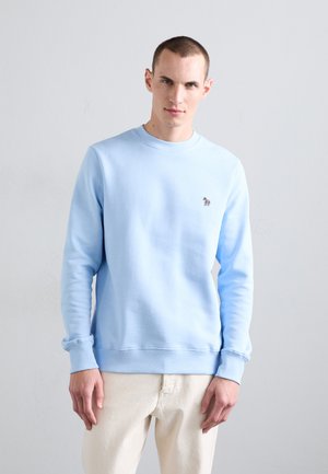 Light blue sweatshirt made of soft fabric, featuring a round neckline and ribbed cuffs, adorned with a small multi-colored logo on the chest.