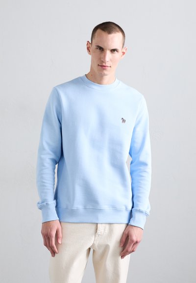 Sweatshirt bleu clair en tissu doux, doté d'un col rond et de poignets côtelés, orné d'un petit logo multicolore sur la poitrine.