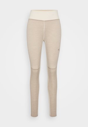 Leggings beiges avec une texture côtelée et une taille solide. Présente des panneaux en maille à motif sur le bas des jambes pour un détail de design supplémentaire.