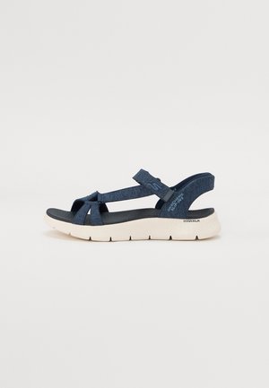 Sandalias deportivas de color azul oscuro con una parte superior texturizada, diseño de tiras cruzadas, correa ajustable en el tobillo y una suela blanca acolchada.