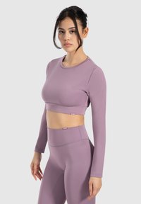 Langärmliges, cropped Oberteil und hoch geschnittene Leggings in helllila, aus dehnbarem, strukturiertem Stoff, mit einem dezenten Markenlogo.