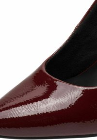 Burgundia läikivast nahast king, millel on terav nina, tekstureeritud pind ja must sisetöö. Elegantne ja voolujooneline siluett.
