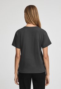 Grå bomullströja med korta ärmar och klassisk rundhals. Slät текстur utan synliga mönster eller utsmyckningar.