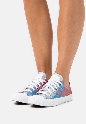 Sneakers in tela multicolore con motivo di macchie rosa e blu, suola in gomma bianca e lacci bianchi con dettagli metallici.