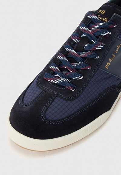 Scarpa da ginnastica blu navy e nera con una combinazione di suede e tessuto strutturato, con lacci decorati e suola in gomma color crema. Scritta dorata sul lato.