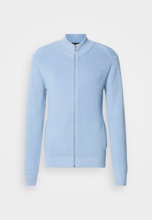 Lys blå zip-up sweater med ribbet struktur, høj krave og lange ærmer. Har en lige kant og sidelommer.