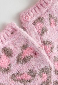 Détail d'un pull tricoté rose flou avec un imprimé léopard marron et rose clair. Il présente un col côtelé et des accents de boutons roses.