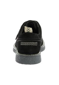 Chaussure en cuir suédé noir avec une texture lisse, semelle en caoutchouc et accents de couture blanche. Le design présente un dos arrondi et des détails gaufrés subtils.