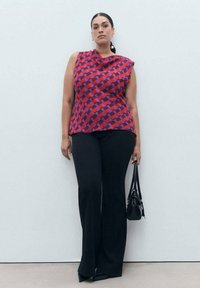 Red and purple checkered sleeveless top paired with black flared trousers. The model carries a small black handbag. Smooth textures throughout.