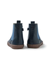 Botas de tobillo de cuero azul oscuro con paneles elásticos azul claro, acabado texturizado, suelas de goma marrón y tiradores en la parte trasera.