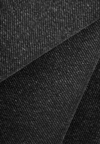 Primer plano de tela de lana gris oscuro que muestra su patrón texturizado y tejido apretado, con capas suaves y dobladas.