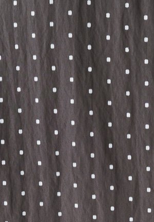 Ciemny materiał z równomiernie rozmieszczonymi, małymi białymi kwadratowymi wzorami o teksturowanej powierzchni. Wzór pokrywa całe tło jednolicie.