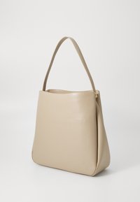 Beige leather bag with a soft, structured design. Features a single, rounded handle and a seamless body with a smooth texture.