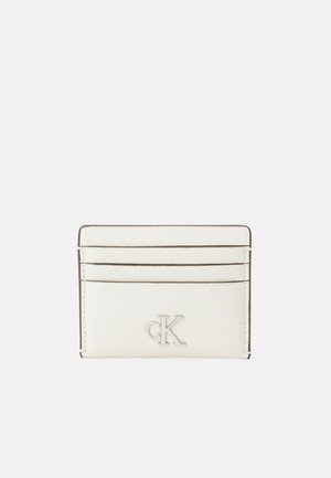 Porte-cartes en cuir blanc avec quatre fentes, logo en relief et couture contrastée. Texture lisse et design minimaliste.