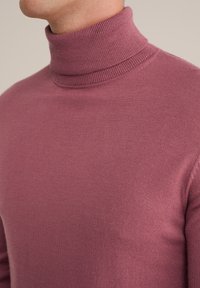 Prilegajoči pulover z visokim ovratnikom v mehkem, roza-roza pletenju. Ima rebrast ovratnik in gladko teksturo, s čistim, minimalističnim dizajnom.