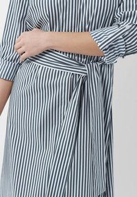 Gestreiftes Kleid in Blau und Weiß, mit einem Wickeldesign, das einen gebundenen Gürtel in der Taille und geknöpfte Manschetten an den Ärmeln aufweist.