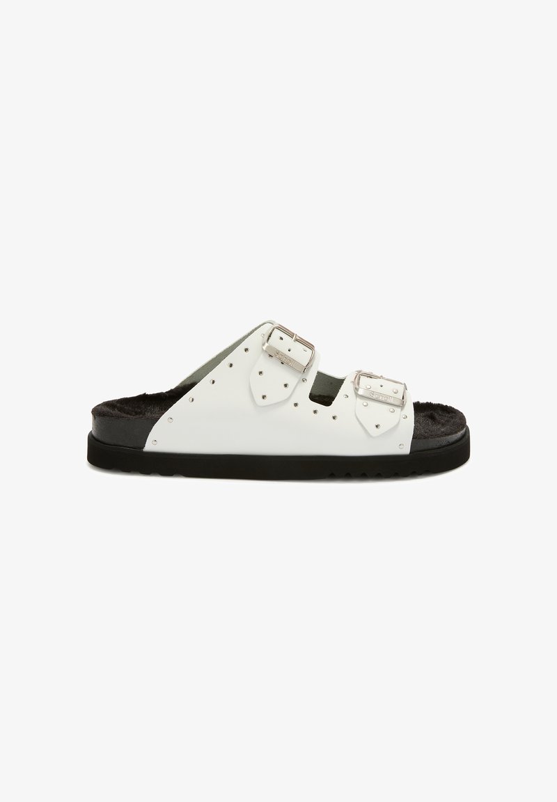 Sandale blanche à glissière avec deux boucles en argent, semelle intérieure en fourrure noire rembourrée et semelle en caoutchouc noir striée, vue de profil.