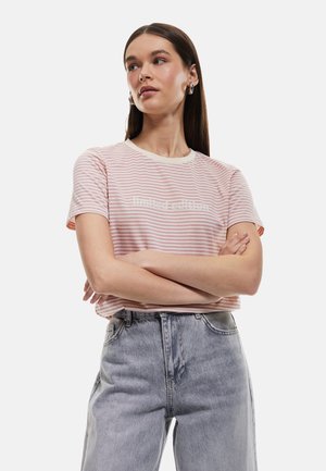 Camiseta de manga corta a rayas rosas con escote redondo y letras blancas, combinada con jeans de mezclilla claros de cintura alta. Textura de tela suave.