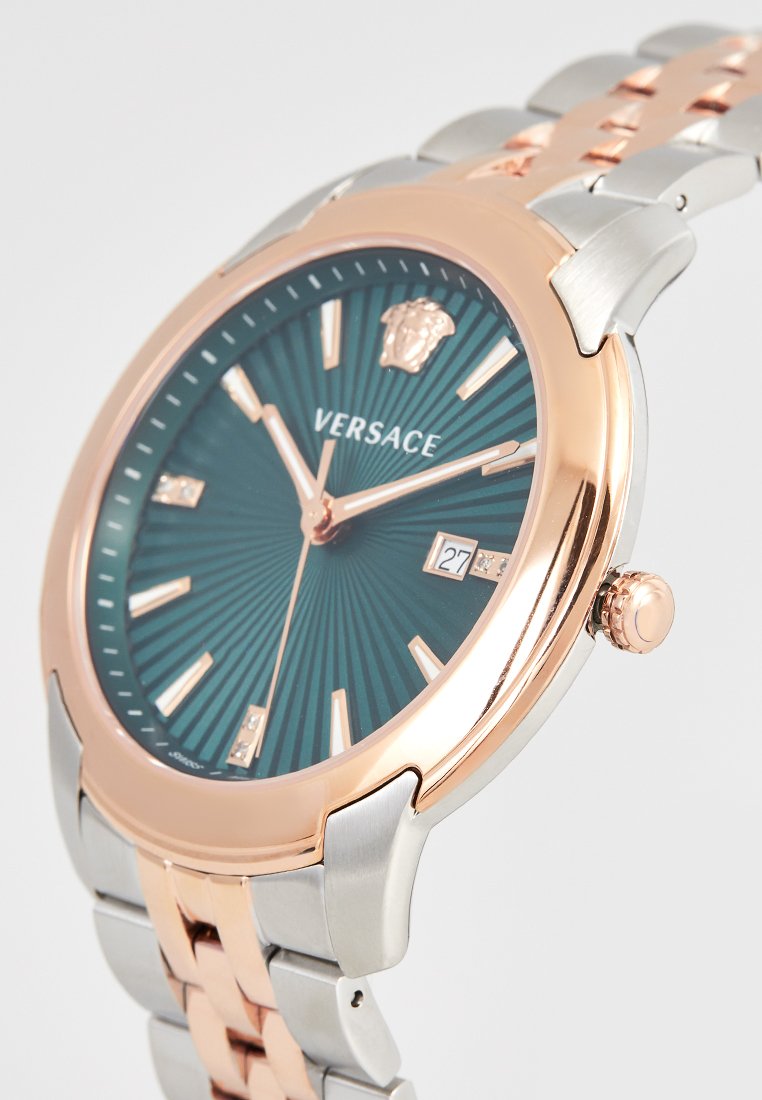 Reloj Versace con una esfera texturizada en tono teal, acentos en oro rosa y una pulsera de acero inoxidable plateado. Incluye una pantalla de fecha y el logo.