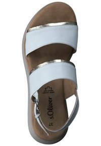 Sandales blanches avec deux larges brides, des accents métalliques dorés, une semelle intérieure rembourrée et une fermeture à boucle sur une semelle beige clair.