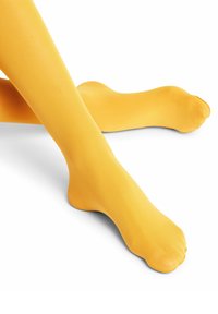 Collant gialli trasparenti con una superficie liscia, design aderente e punta rinforzata, mostrati su uno sfondo bianco.