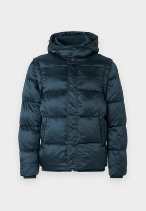 Veste d'hiver rembourrée de couleur vert foncé avec un col haut, une capuche, une fermeture éclair sur le devant, des poches latérales et des poignets côtelés sur un fond blanc uni.