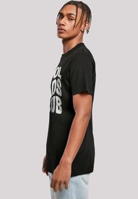 Zwart katoenen T-shirt met een ronde halslijn, voorzien van grote witte tekst "COOL KIDS CLUB" op de voorkant. Korte mouwen, comfy pasvorm.