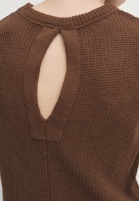 Bruine gebreide trui met een ronde halslijn en een kenmerkende sleutelgat uitsnede op de rug. Getextureerde stof en ribbelranden.