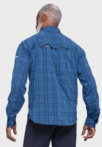 Blau kariertes Langarmhemd mit Knopfmanschetten, lockerer Passform und einer Belüftung am Rücken für Atmungsaktivität. Glattes, leichtes Material.