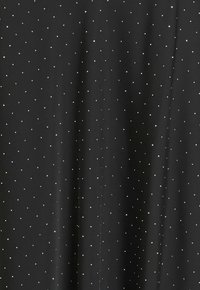 Svart tyg med små vita prickar. Slät textur, lättviktig design, jämnt fördelade prickar skapar ett mönster över ytan.