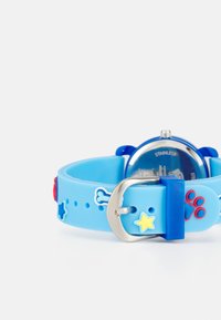 Pulseira de relógio de silicone azul com desenhos de osso, estrela e pegada de pata. Fivela em aço inoxidável. Mostrador de relógio redondo com uma borda azul e fundo transparente.