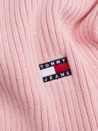Tessuto lavorato a maglia rosa con texture a coste; presenta un'etichetta logo colorata con il testo "TOMMY JEANS" e strisce rosse, bianche e blu.