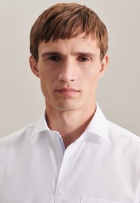 Weißes Button-Up-Hemd mit einem hellblauen Kragen. Verfügt über eine strukturierte Passform und glattes Baumwollmaterial und präsentiert ein sauberes, modernes Design.