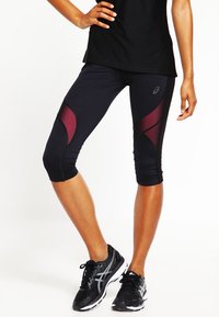 Leggings deportivos negros con paneles de acento burdeos, de longitud hasta la mitad de la pantorrilla, fabricados con material elástico; presenta un detalle del logo en el lado.