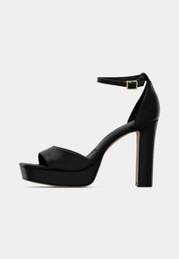 Mustat avoimet, nahasta tehdyt korkeakorkoiset sandaalit. Niissä on nilkkaremmi ja paksu korko platatformipohjalla.
