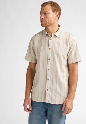 Beżowa koszula z krótkim rękawem zapinana na guziki, z pionowymi jasnymi i ciemnymi paskami. Ozdobiona drewnianymi guzikami i luźnym kołnierzem.