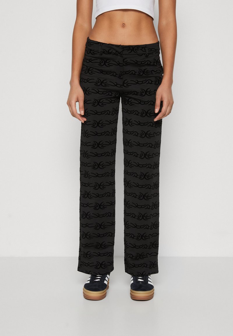 Zwarte wijde broek met een textuurpatroon van herhalende krullen. Gemaakt van een zacht materiaal met een aansluitende taille.