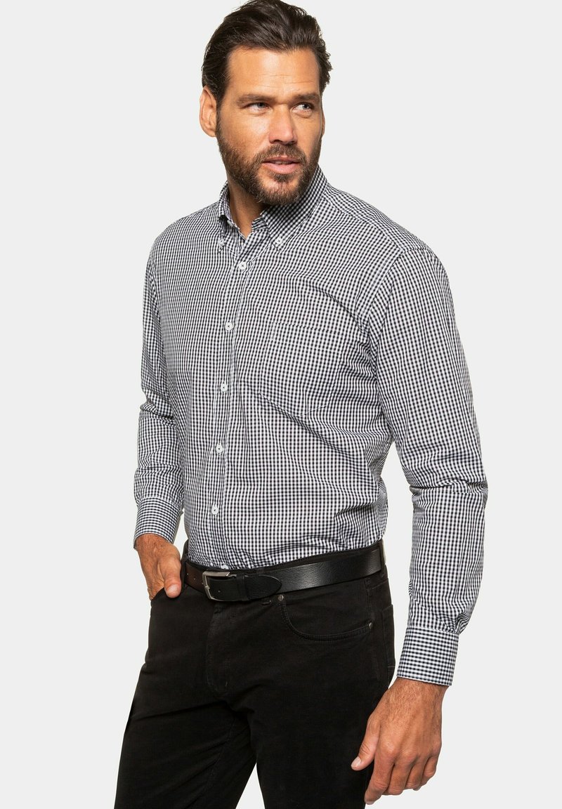 Black and white checked button-up shirt with long sleeves, a collared neckline, and a smooth fabric texture, paired with black pants and belt.